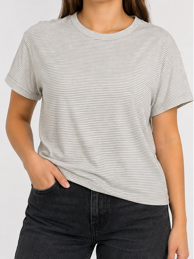 Modelo mujer con polera Eddie Bauer a rayas finas blancas y grises, imagen referencial
