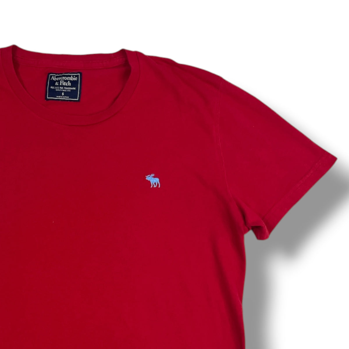 Detalle frontal polera roja con alce celeste bordado
