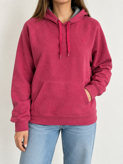 Modelo mujer, vista frontal con polerón Champion rosado (imagen referencial)