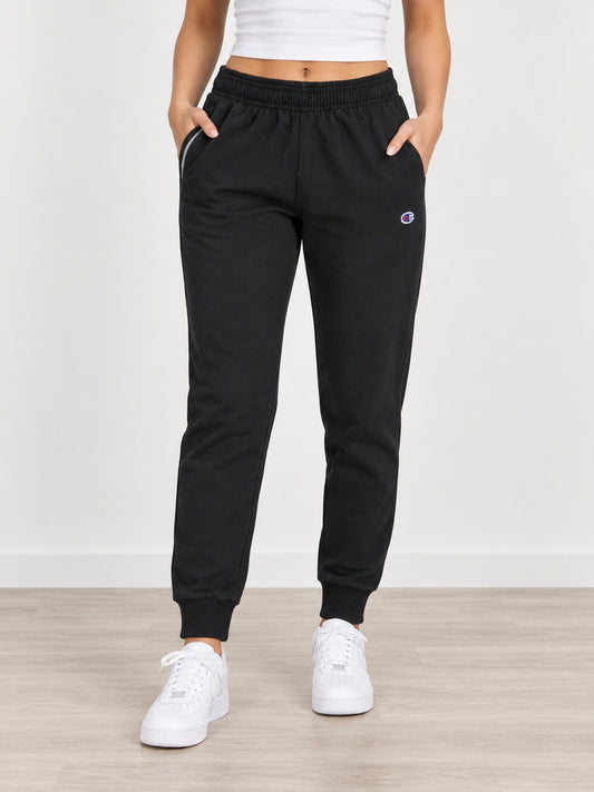Foto referencial frontal del pantalón de buzo Champion negro con modelo mujer